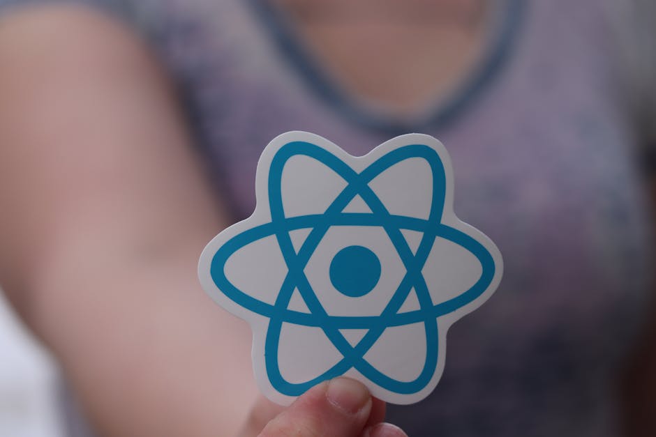 Close-up of a person's hand holding a sticker with a blue atom symbol, indicating a focus on surface cleaning and sanitisation. The background features a blurred view of a person's torso wearing a pur